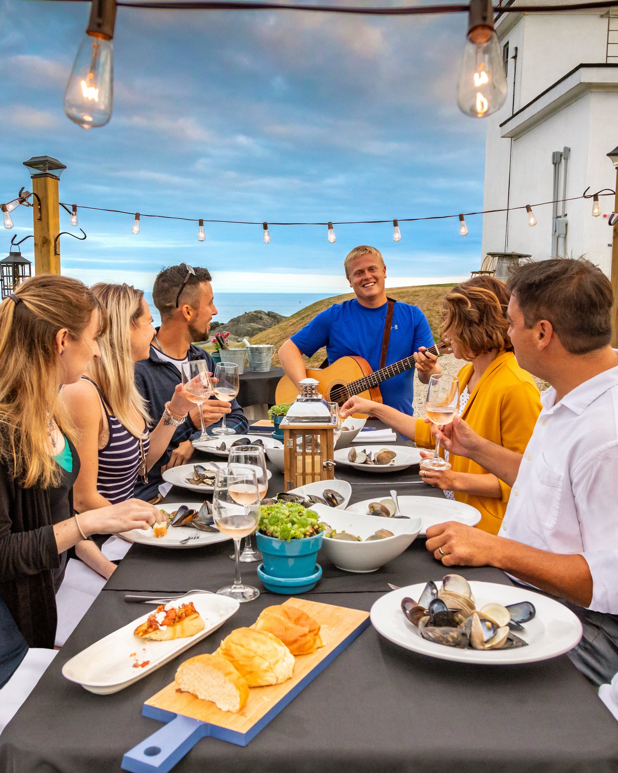 A family eating dinner with a man serenading them on the guitar
