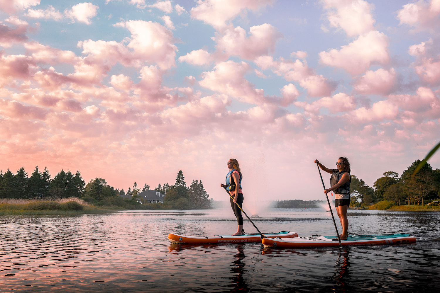 Two women on paddle boards at sunset