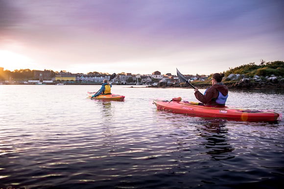 Two people in separate kayaks at sunset