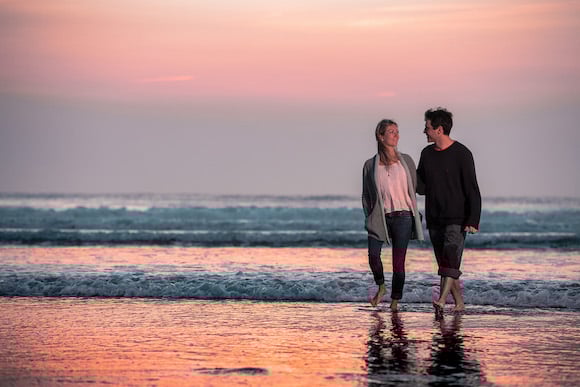 Man and woman walking on the beach at sunset