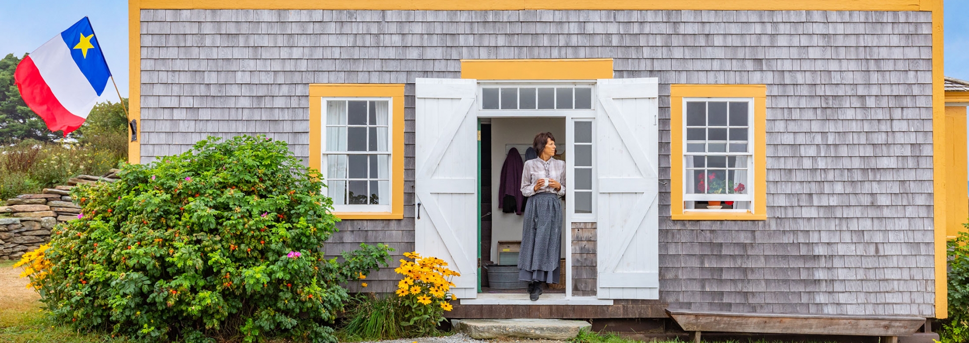 Women standing in the doorway of a wood-sided house with yellow trim