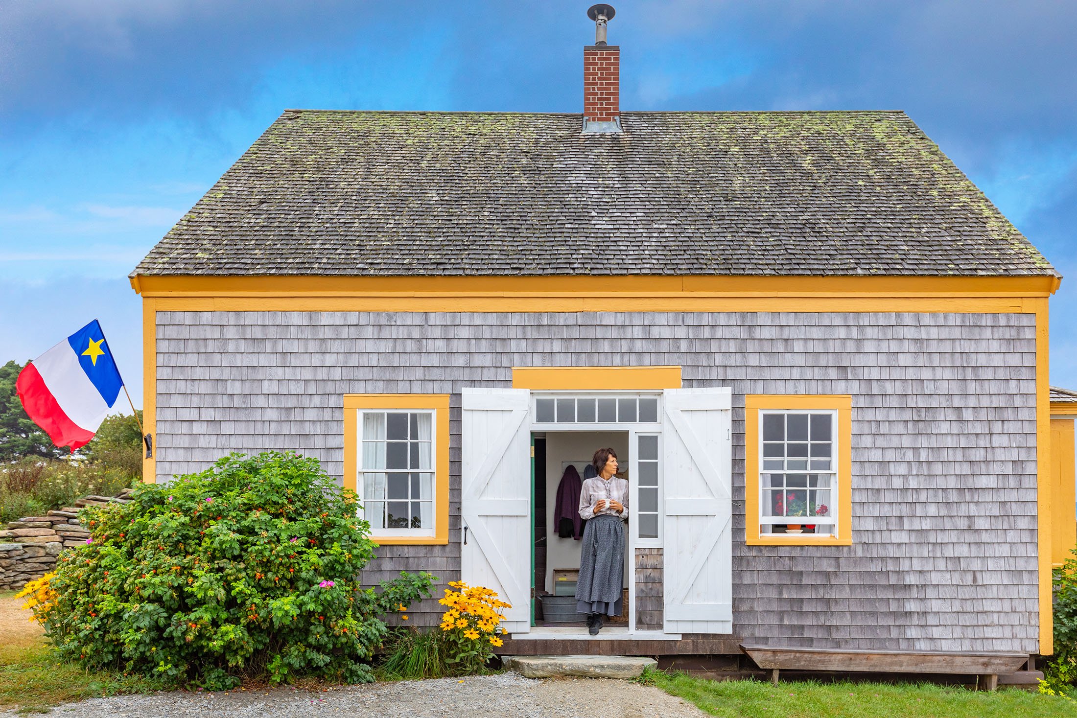 Women standing in the doorway of a wood-sided house with yellow trim