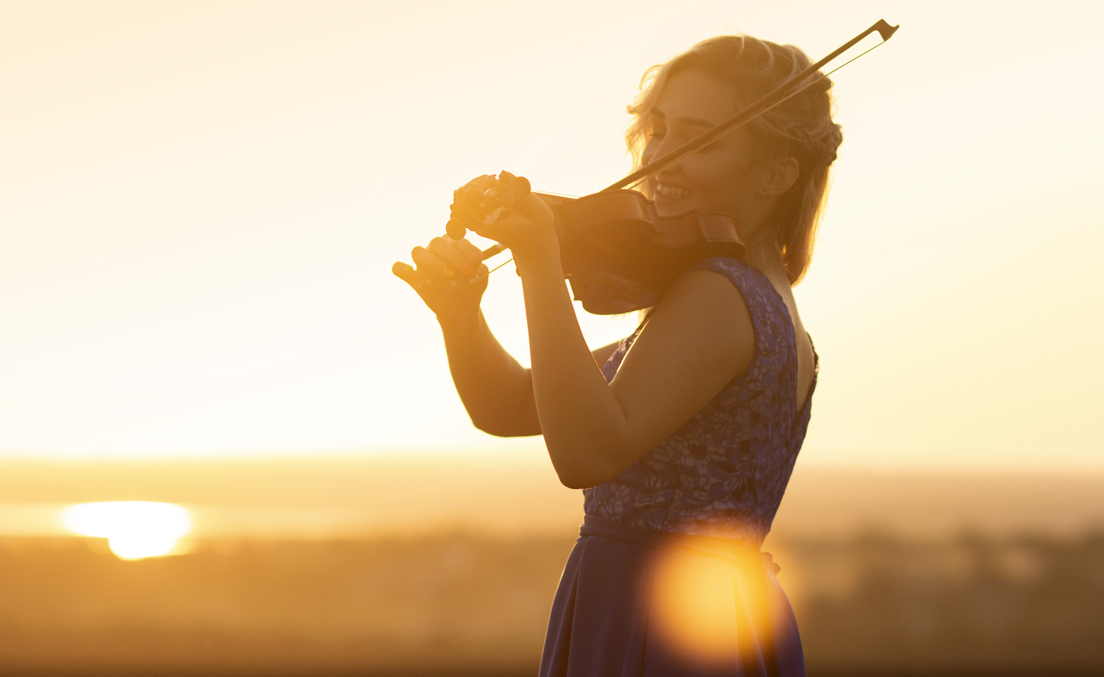 A woman playing the fiddle outdoors