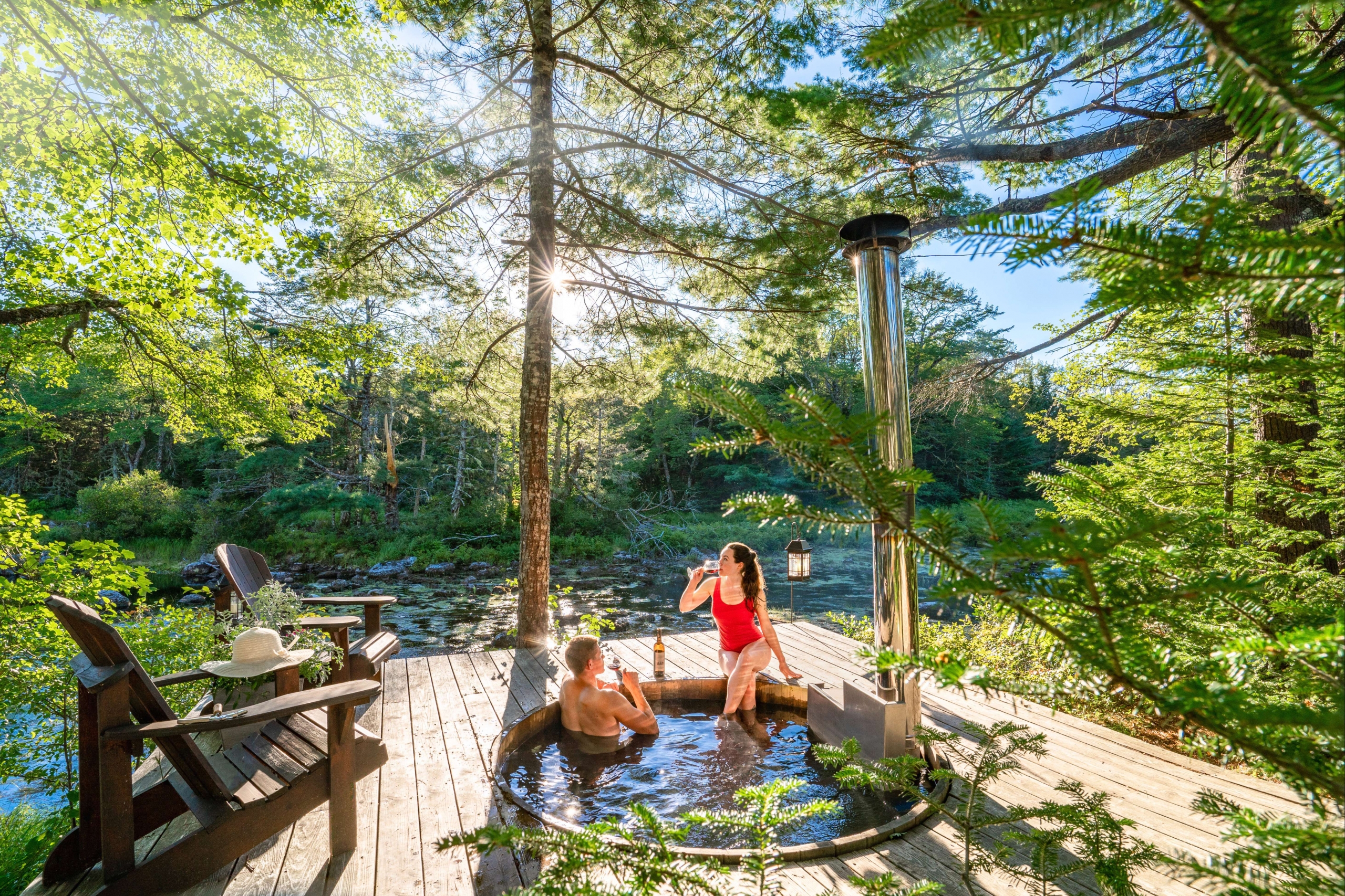 A couple having drinks in an outdoor jacuzzi in the woods